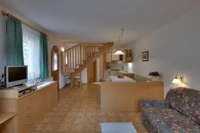 a living room with a couch and a kitchen at Villa Martha ex Garnì Oskar in Corvara in Badia