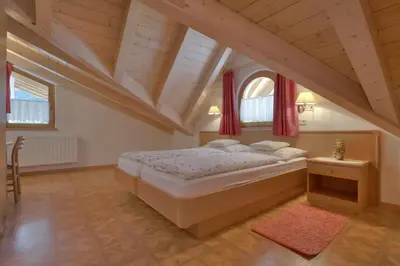 a bedroom with a large bed and two windows at Villa Martha ex Garnì Oskar in Corvara in Badia