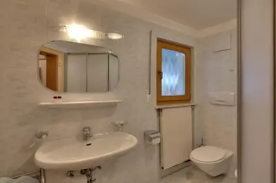 a bathroom with a sink and a toilet and a mirror at Villa Martha ex Garnì Oskar in Corvara in Badia