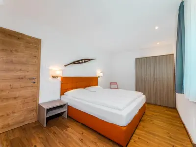 a bedroom with a large white bed and a wooden floor at Residence Brunello in Ortisei