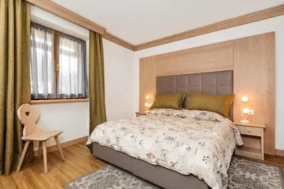 a bedroom with a bed and a desk and a chair at Hotel Pontechiesa in Cortina dʼAmpezzo