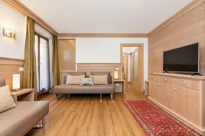 a living room with a couch and a flat screen tv at Hotel Pontechiesa in Cortina dʼAmpezzo