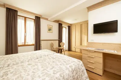 a bedroom with a bed and a flat screen tv at Hotel Pontechiesa in Cortina dʼAmpezzo