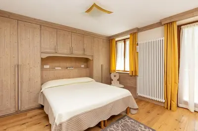 a bedroom with a white bed and yellow curtains at Hotel Pontechiesa in Cortina dʼAmpezzo