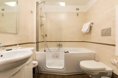 a bathroom with a tub and a toilet and a sink at Hotel Pontechiesa in Cortina dʼAmpezzo