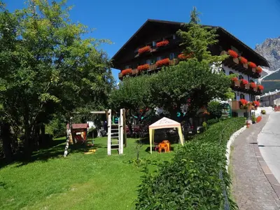 a building with a lot of flowers in front of it at Hotel Pontechiesa in Cortina dʼAmpezzo