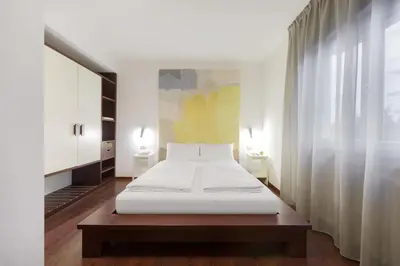 a bedroom with a white bed and a large window at Hotel Asterix in Bolzano