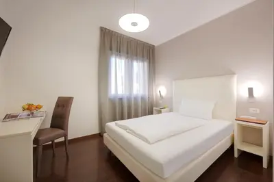a bedroom with a white bed and a desk and a chair at Hotel Asterix in Bolzano