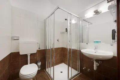 a bathroom with a shower and a toilet and a sink at Hotel Asterix in Bolzano