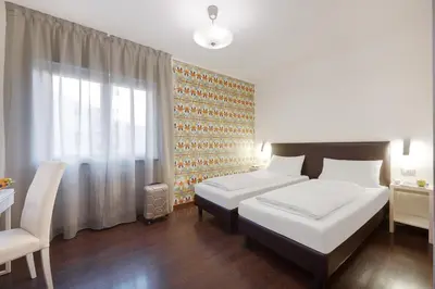 a hotel room with two beds and a window at Hotel Asterix in Bolzano