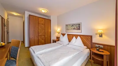 a bedroom with a large white bed and a desk at Hotel Millanderhof in Bressanone