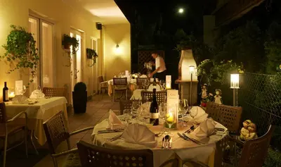 a restaurant with tables with white tablecloths and a man in the background at Hotel Millanderhof in Bressanone