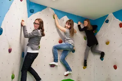 three girls are climbing a rock wall at Hotel Millanderhof in Bressanone