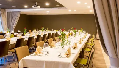 a long table with white tables and chairs in a room at Hotel Millanderhof in Bressanone