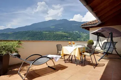 a patio with a table and chairs and an umbrella at Hotel Millanderhof in Bressanone