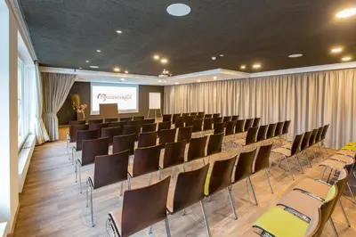 a lecture hall with chairs and a screen and a podium at Hotel Millanderhof in Bressanone