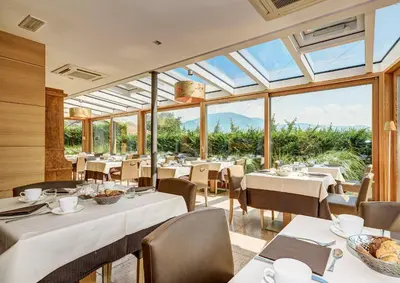 a restaurant with tables and chairs and windows at Art & Design Hotel Napura in Bolzano