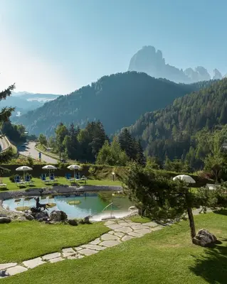 a park with a swimming pool with mountains in the background at Diamant Spa Resort in Santa Cristina in Val Gardena