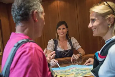 a woman sitting at a table talking to two women at Diamant Spa Resort in Santa Cristina in Val Gardena