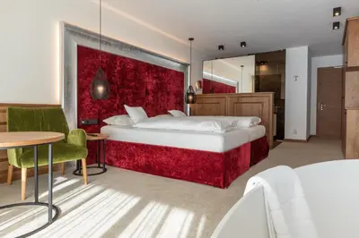 a bedroom with a large bed with a red wall at Diamant Spa Resort in Santa Cristina in Val Gardena