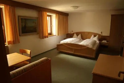a bedroom with a large bed and a table at gasthof pension rössl in Nova Ponente