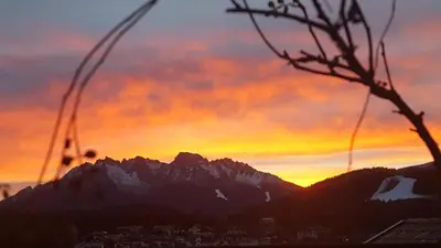a sunset over a city with a mountain at gasthof pension rössl in Nova Ponente