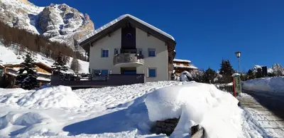 a house covered in snow in the mountains at App. Villa Fraina in San Cassiano