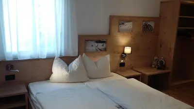 a bedroom with a bed with white sheets and pillows at App. Villa Fraina in San Cassiano