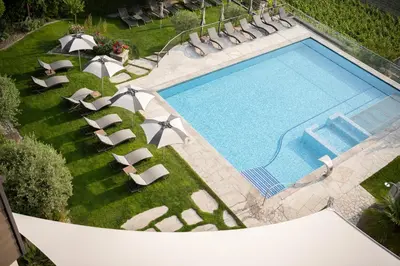 an overhead view of a swimming pool with lounge chairs and an infinity at Hotel Resmairhof in Schenna
