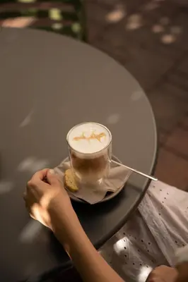 a person holding a cup of coffee on a table at Hotel Resmairhof in Schenna