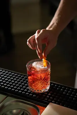 a person is putting an orange slice in a drink at Hotel Resmairhof in Schenna