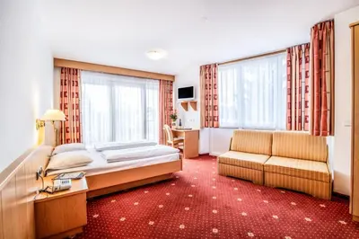 a hotel room with a bed and a couch at Hotel Mondschein in Vipiteno