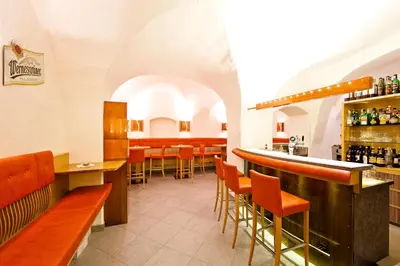 a bar in a restaurant with orange stools at Hotel Mondschein in Vipiteno