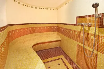 a large bathroom with a shower with a mosaic floor at Hotel Mondschein in Vipiteno