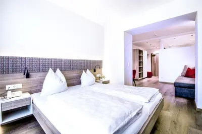 a large white bedroom with a large bed and a couch at Hotel Mondschein in Vipiteno