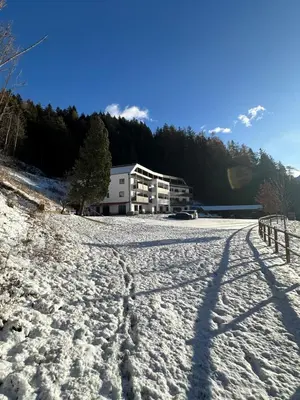 a snow covered field with a building in the background at Hotel Larch in Campo di Trens