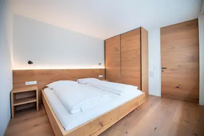 a bedroom with a large white bed with wooden walls at Villa Mayr in Ortisei