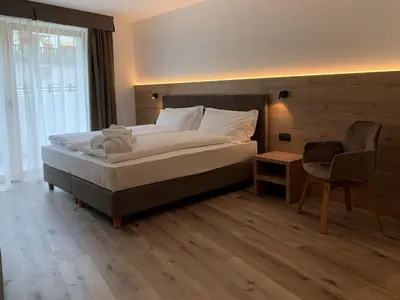 a bedroom with a large bed and a chair at Hotel Miravalle in Soraga