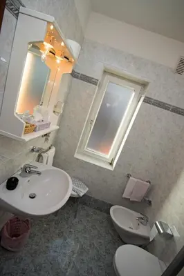 a bathroom with a sink and a mirror and a toilet at Hotel Miravalle in Soraga