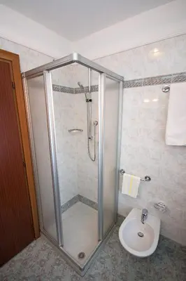 a bathroom with a shower and a toilet and a sink at Hotel Miravalle in Soraga