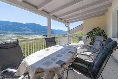 a porch with a table and chairs on a balcony at Quellenhof in Termeno
