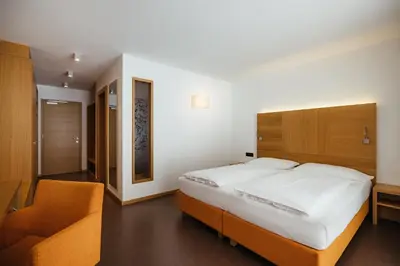 a bedroom with a bed and a desk and a window at Hotel Melodia del Bosco in Badia