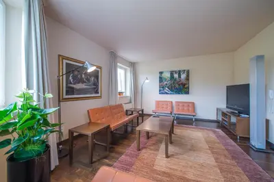 a living room with orange chairs and a flat screen tv at Seegarten in Caldaro