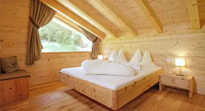 a bed in a wooden room with a window at Chalet Oberguggenberg in San Lorenzo di Sebato