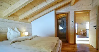 a bedroom with a large bed in a wooden building at Chalet Oberguggenberg in San Lorenzo di Sebato