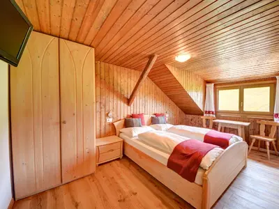 a bed in a room with a wooden ceiling at Tötscherhof in Terento