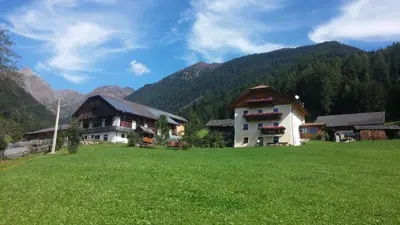 a house in a field with mountains in the background at Tötscherhof in Terento