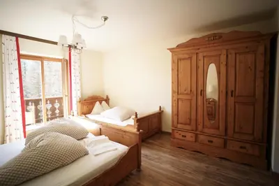 a bedroom with two beds and a wooden cabinet at Gstattlhof Mountain Farmhouse in Braies