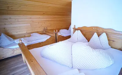 a bedroom with two beds in a log cabin at Gstattlhof Mountain Farmhouse in Braies