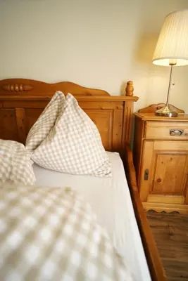 a bed with two pillows and a lamp on a table at Gstattlhof Mountain Farmhouse in Braies